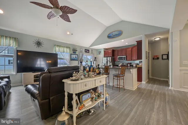 a living room with stainless steel appliances furniture wooden floor and a kitchen view