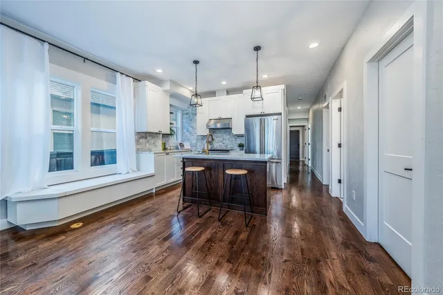 a large kitchen with a wooden floor and stainless steel appliances