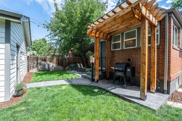 a view of a backyard with a table and chairs and a large tree
