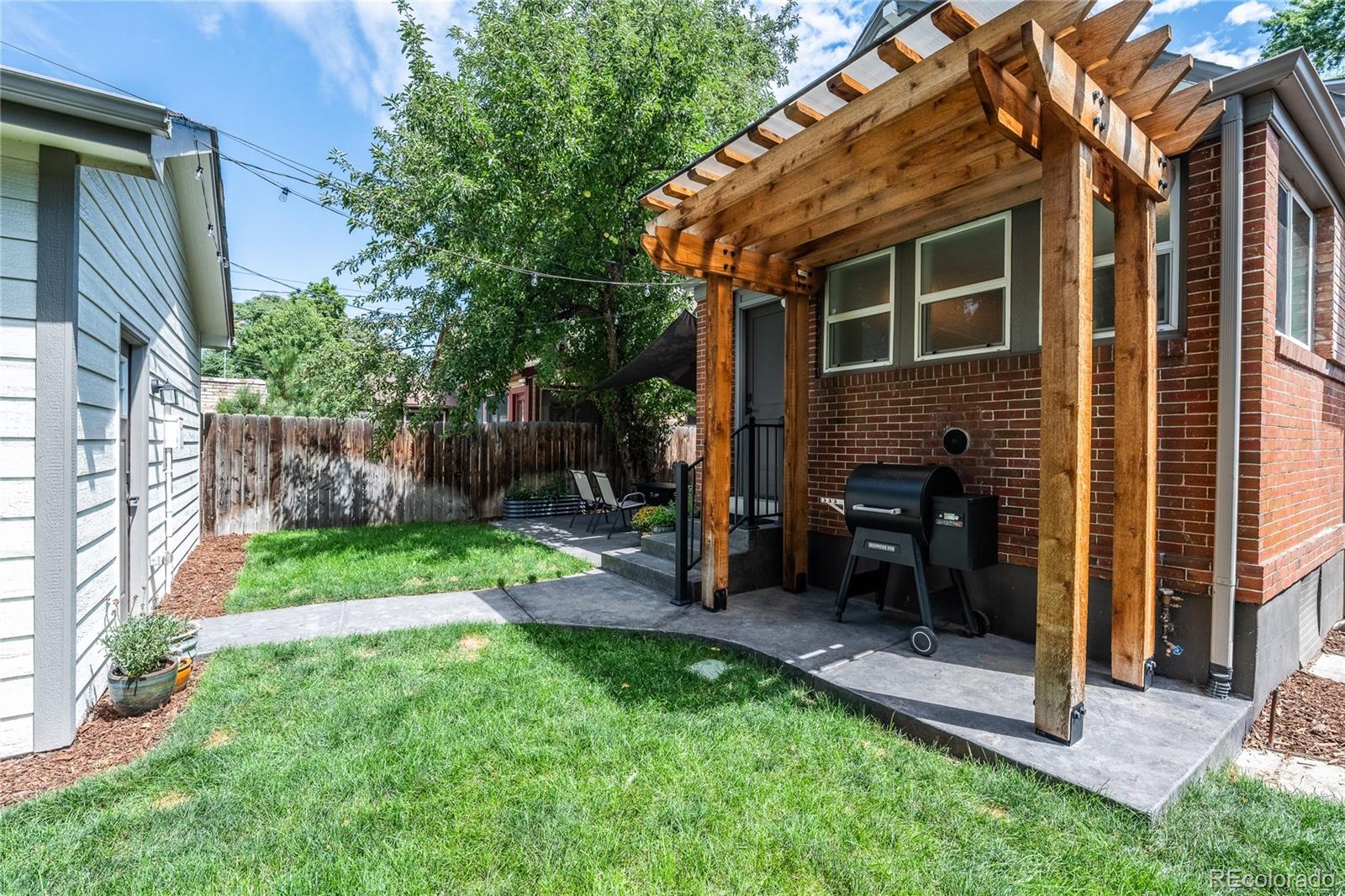 1367 Monroe Street Denver, CO 80206 - Photo 39 of 48 a view of a backyard with a table and chairs and a large tree