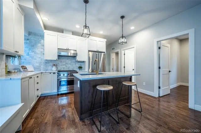 a large kitchen with granite countertop a sink a counter space stainless steel appliances and cabinets