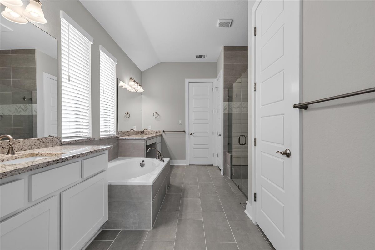 320 Raptor Beak Way Cedar Creek, TX 78612 - Photo 28 of 40 Luxurious primary bath features dual granite-topped vanities, a deep soaking tub, and a spacious glass-enclosed shower.