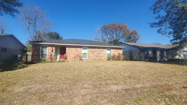 a front view of house with yard and trees in the background