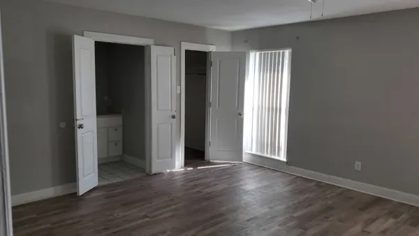 an empty room with wooden floor & windows