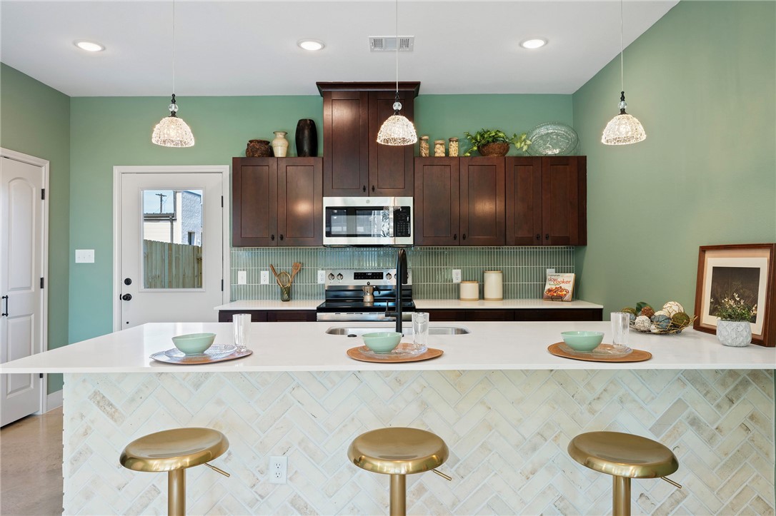 102 33rd Street West Bryan, TX 77803 - Photo 4 of 22 a kitchen with stainless steel appliances granite countertop a sink a stove a refrigerator cabinets and chairs