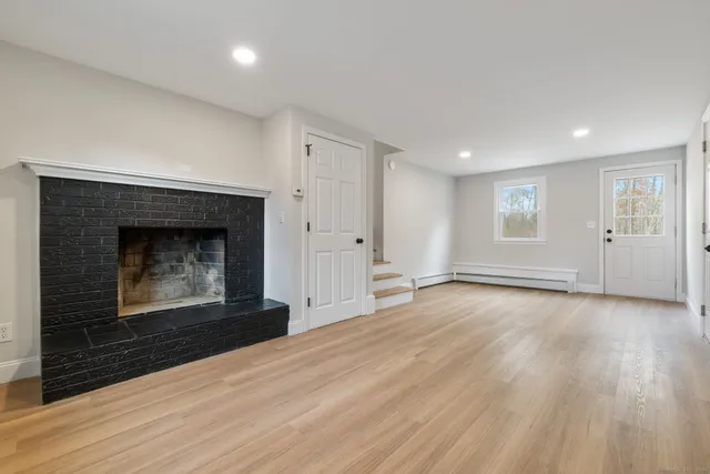 an empty room with wooden floor fireplace and windows