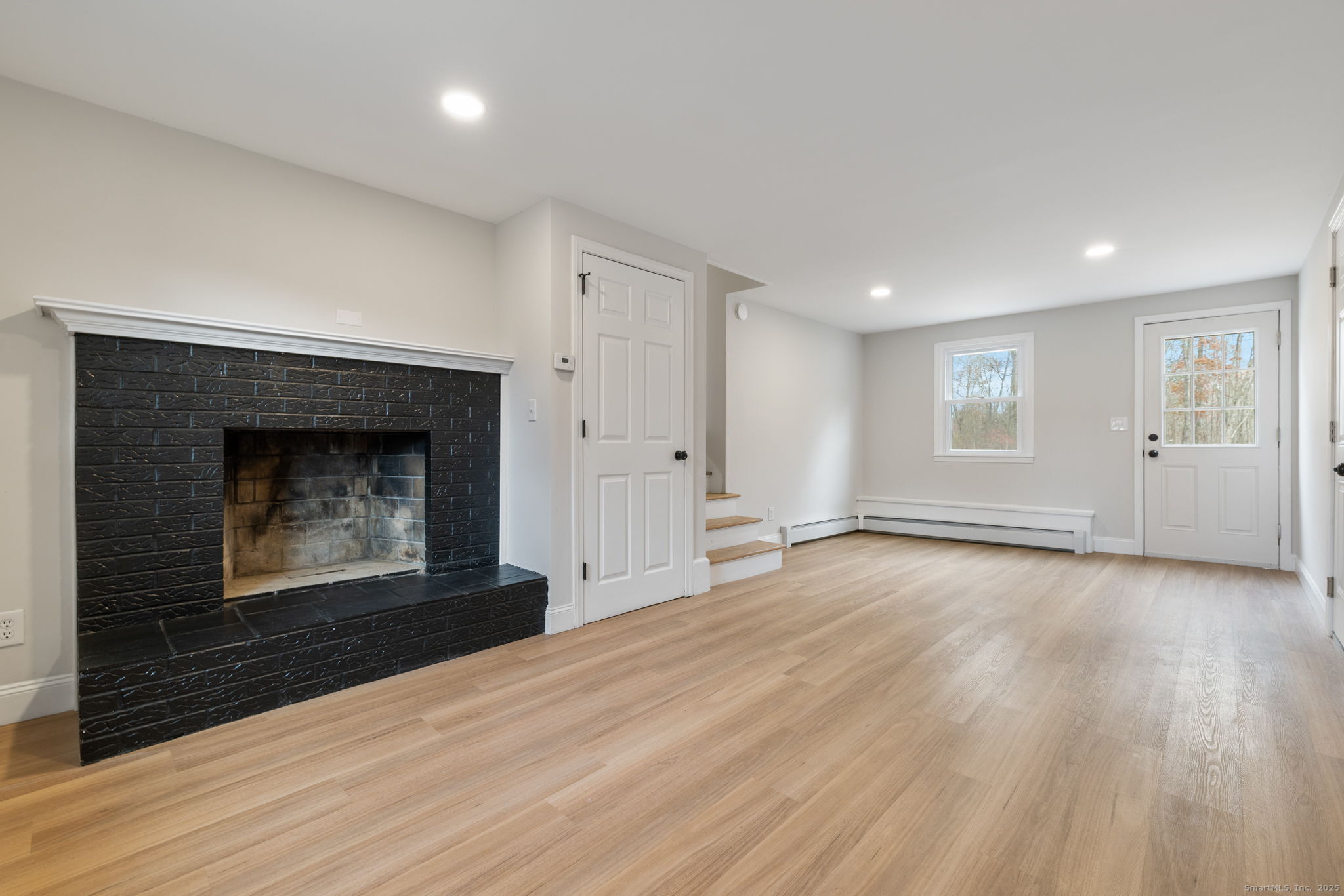 410 South Stone Street Suffield, CT 06093 - Photo 12 of 23 an empty room with wooden floor fireplace and windows