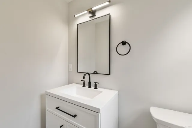 a bathroom with a toilet sink vanity and mirror