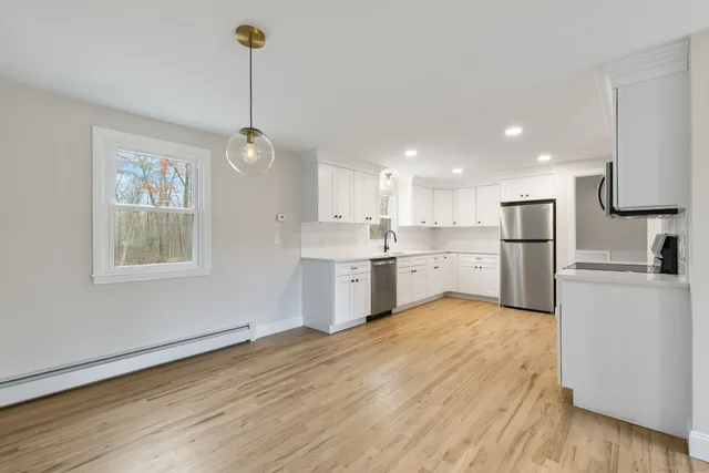 a kitchen with stainless steel appliances granite countertop a refrigerator a sink dishwasher a stove and white countertops with wooden floor