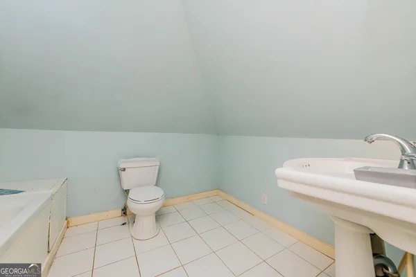 a view of a hallway with wooden floor and a bathroom