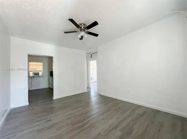 a view of empty room with wooden floor and white walls