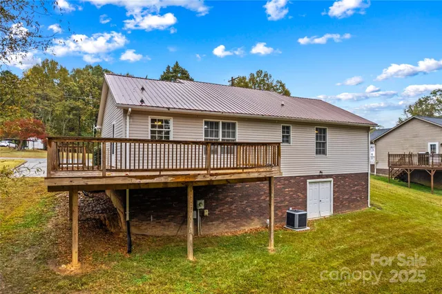 a backyard of a house with wooden deck and outdoor seating