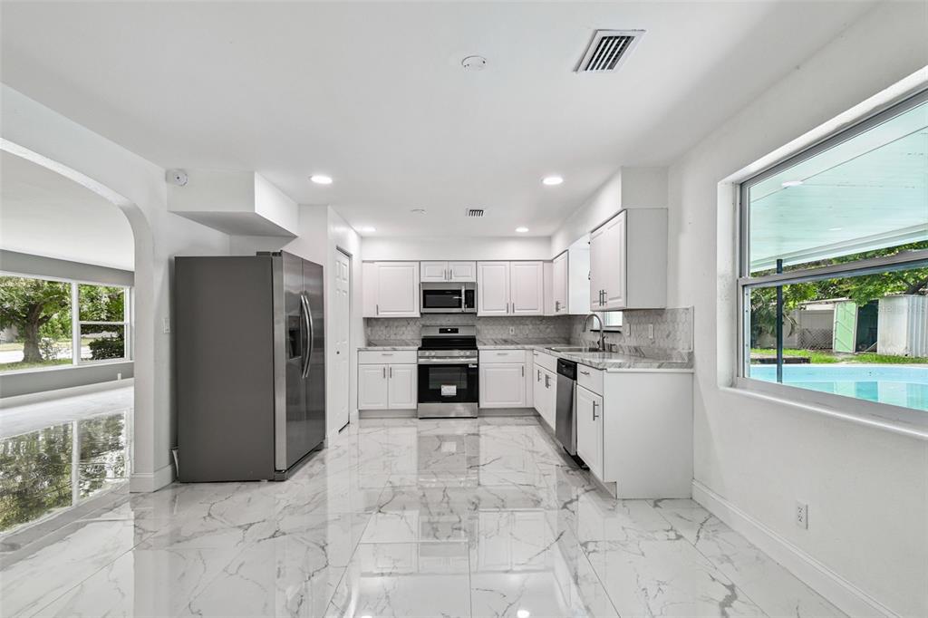 6016 Arthur Avenue New Port Richey, FL 34653 - Photo 18 of 33 a large white kitchen with stainless steel appliances granite countertop a refrigerator and a stove top oven