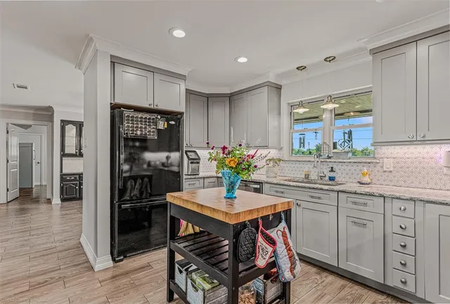 a kitchen with kitchen island granite countertop a sink cabinets and wooden floor