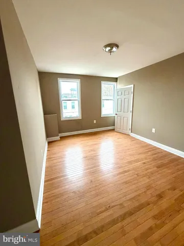 a view of empty room with window and wooden floor
