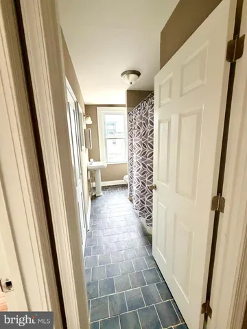 a view of an empty room with wooden floor and a bathroom