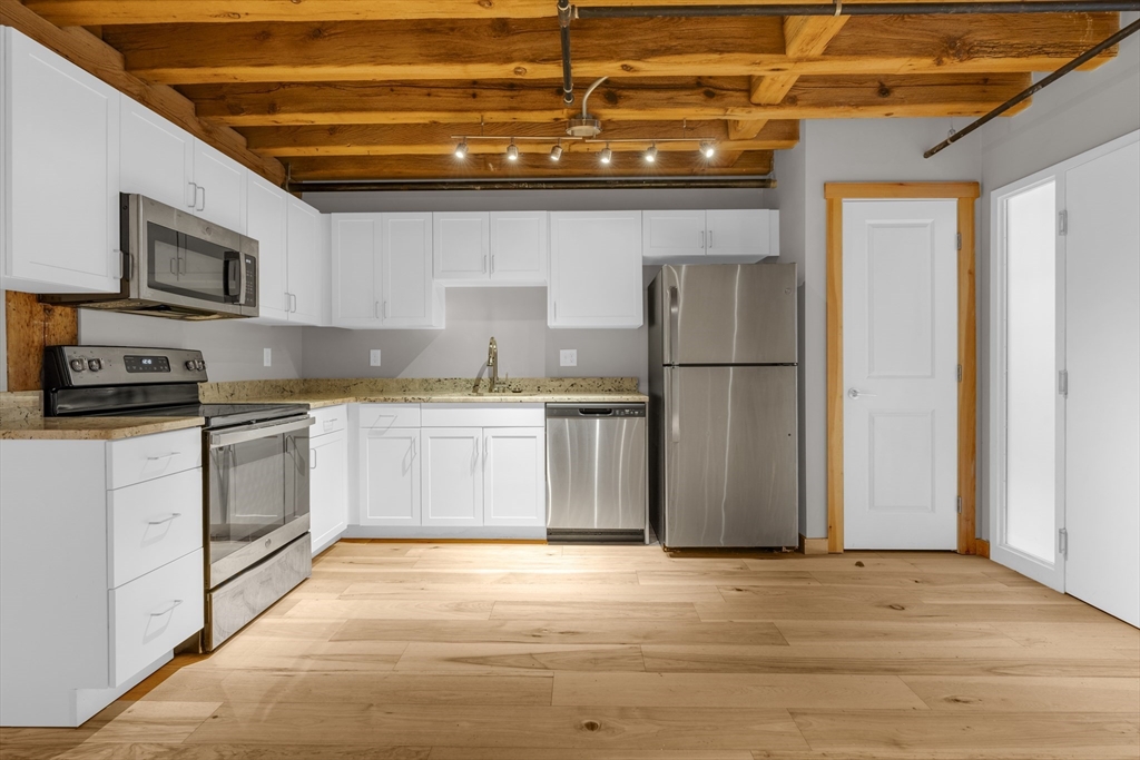 58 13th Street, Unit 112 Boston, MA 02129 - Photo 2 of 11 a kitchen with a sink cabinets stainless steel appliances and a window