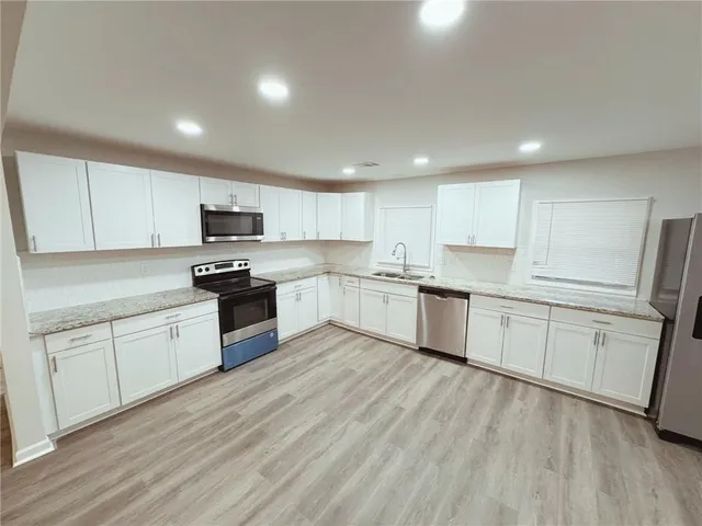a kitchen with white cabinets stainless steel appliances and a sink