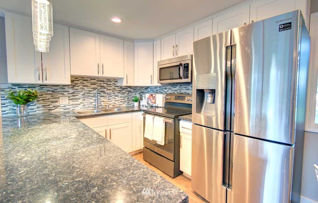 866 Queen Avenue Northeast Renton, WA 98056 - Photo 3 of 15 a kitchen with stainless steel appliances granite countertop a refrigerator a microwave a sink and white cabinets