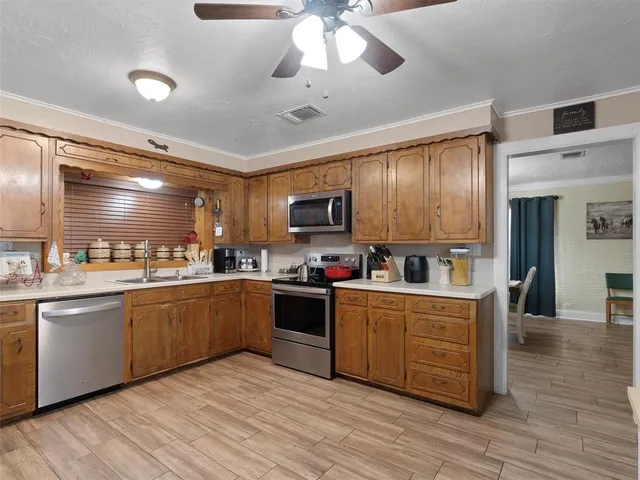 a kitchen with stainless steel appliances granite countertop a sink cabinets and wooden floor