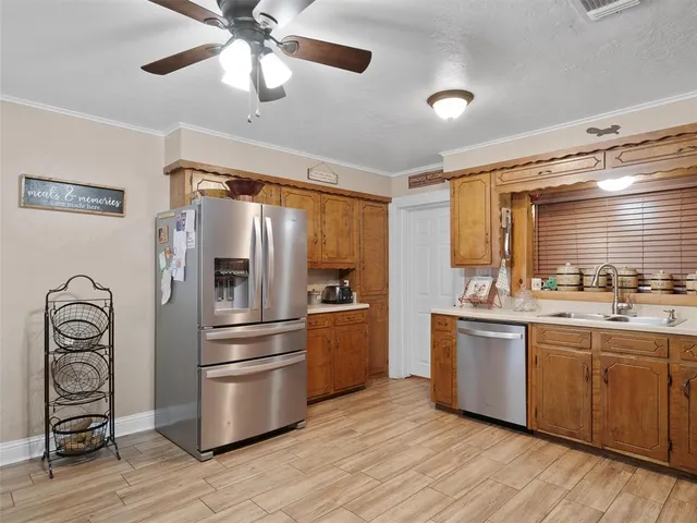 a kitchen with stainless steel appliances granite countertop a refrigerator a stove and a sink with wooden floors