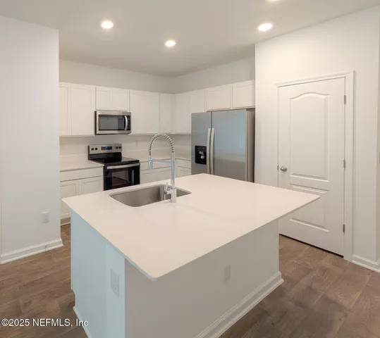 a kitchen with stainless steel appliances a white refrigerator a sink a stove a microwave and cabinets