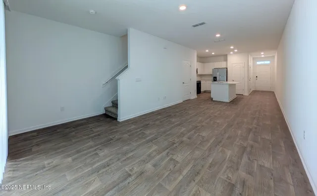 a view of a livingroom with a kitchen counter space and wooden floor