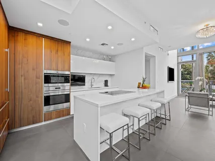 a large kitchen with stainless steel appliances a stove a sink dishwasher and a refrigerator with wooden floor