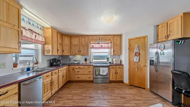 a kitchen with stainless steel appliances granite countertop a refrigerator a sink dishwasher a stove with wooden cabinets and floor