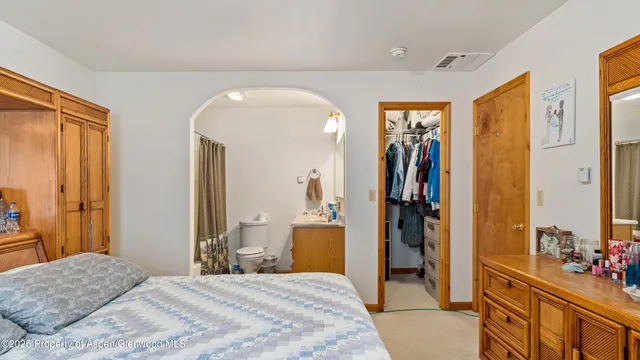 a bedroom with a bed mirror and a dresser