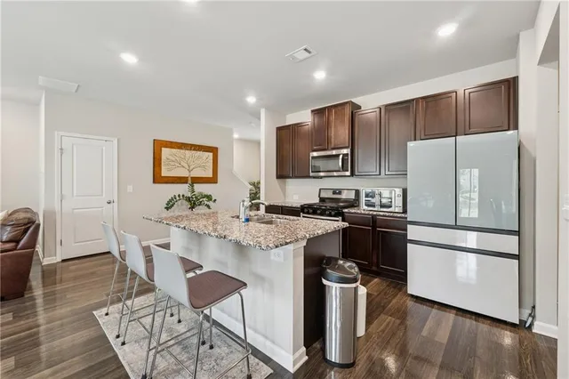 a kitchen with stainless steel appliances a refrigerator a stove a sink a dining table and chairs