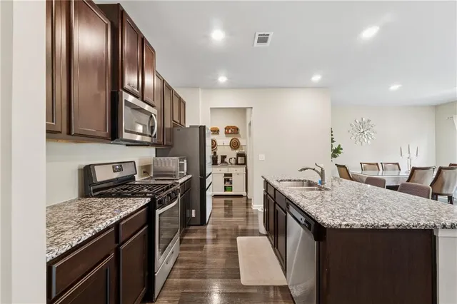 a kitchen with stainless steel appliances granite countertop a kitchen island a stove a refrigerator and a sink