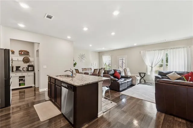 a living room with stainless steel appliances kitchen island granite countertop a table and chairs in it