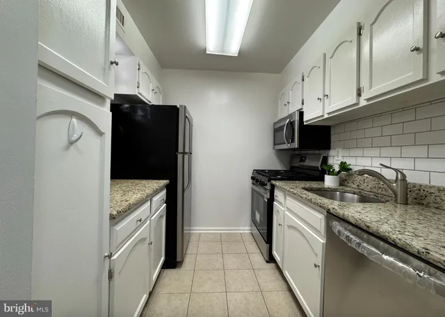 a kitchen with granite countertop a refrigerator and a sink
