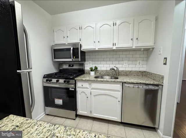 a kitchen with stainless steel appliances granite countertop a stove a refrigerator and a sink
