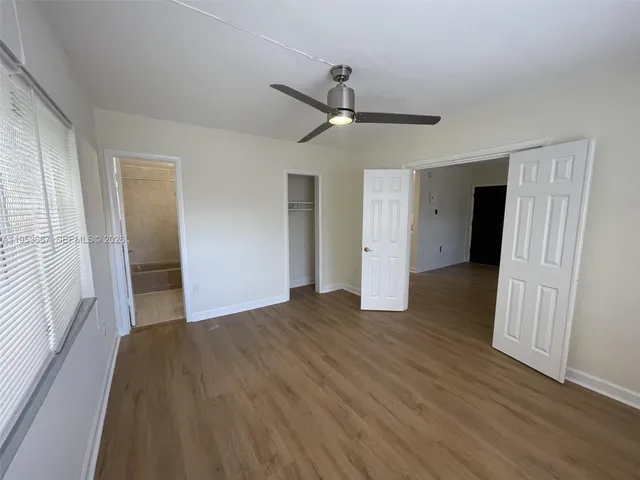 a view of empty room with wooden floor and fan