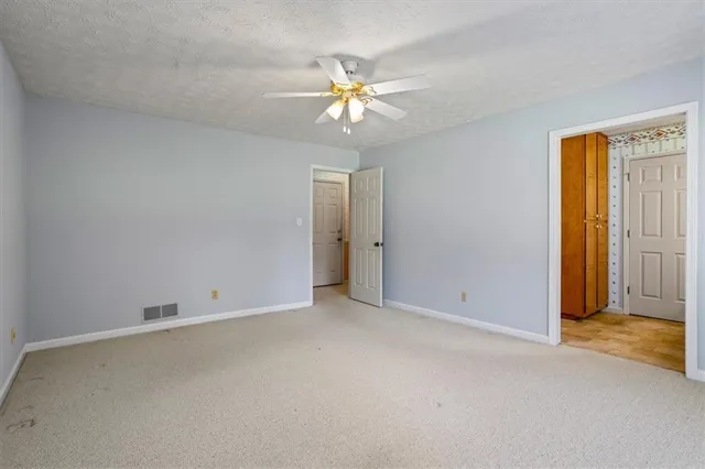 an empty room with closet and a chandelier fan