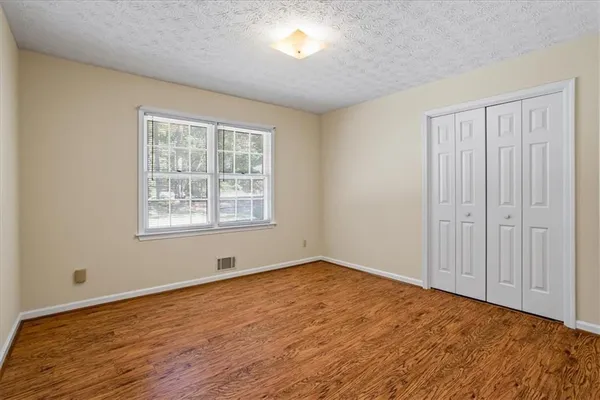 a view of an empty room with wooden floor and a window