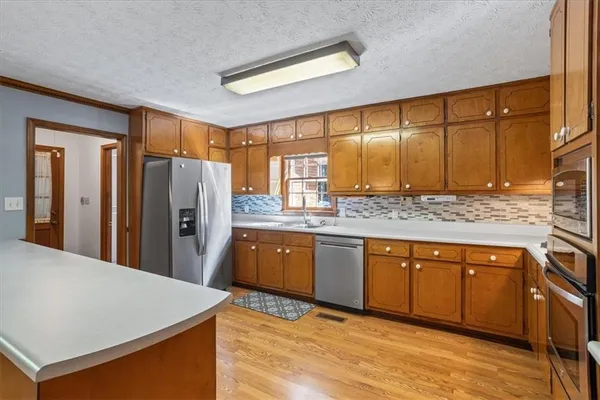 a kitchen with stainless steel appliances granite countertop a refrigerator a sink dishwasher a stove with wooden cabinets and floor