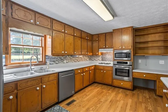 a kitchen with stainless steel appliances sink cabinets and window
