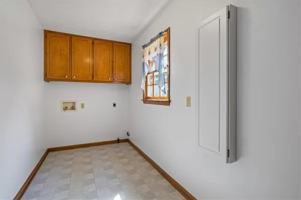 a view of hallway with paintings on the wall and a window