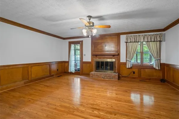 a view of an empty room with a window and wooden floor