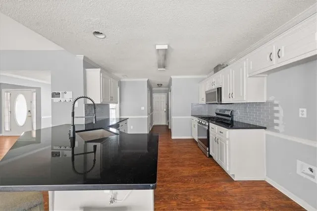 a large kitchen with stainless steel appliances granite countertop a sink a stove and a refrigerator