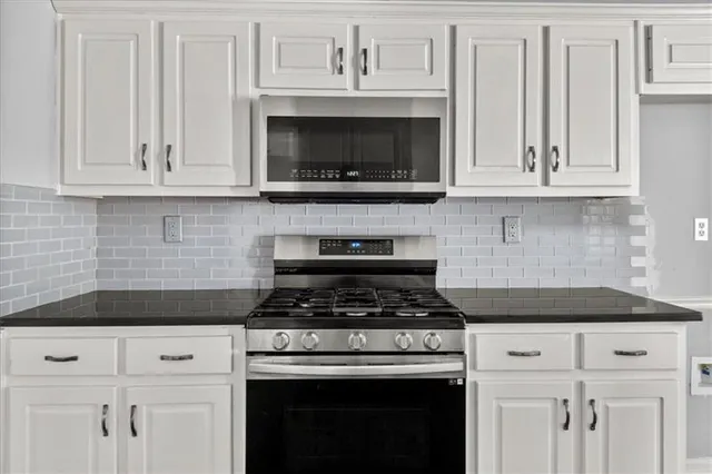 a kitchen with white cabinets and black appliances