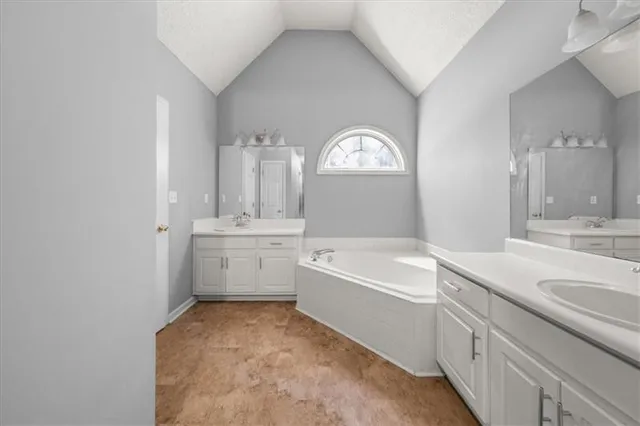 a bathroom with a sink a bathtub a mirror a vanity and a bathtub