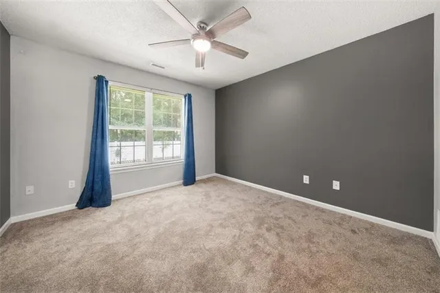 an empty room with windows and fan