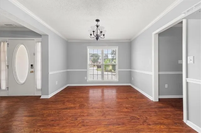a view of an empty room with window and wooden floor