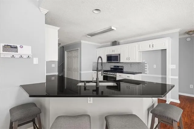 a kitchen with stainless steel appliances granite countertop a dining table chairs and a refrigerator