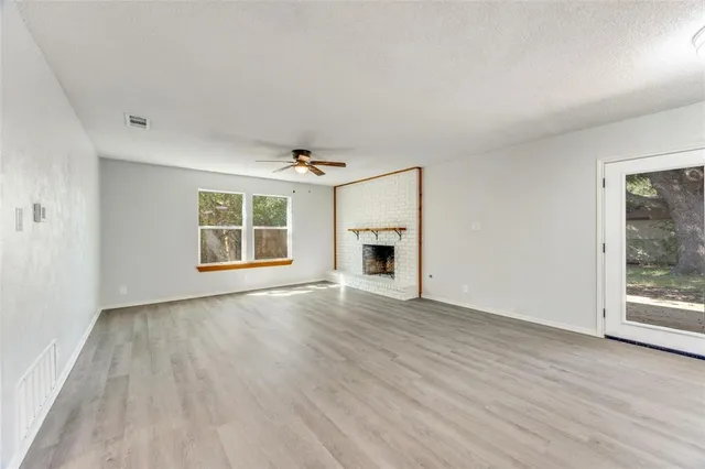 an empty room with wooden floor a fireplace and windows