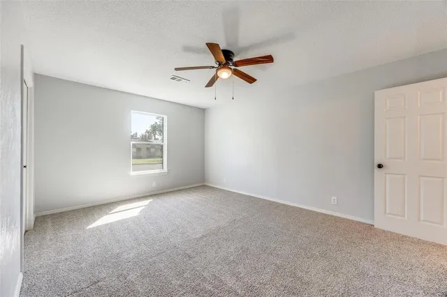 an empty room with windows and fan
